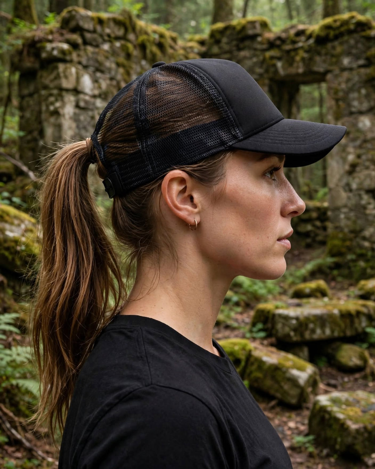 Side view of a woman in the black R.Mikal trucker hat with ponytail and mesh back