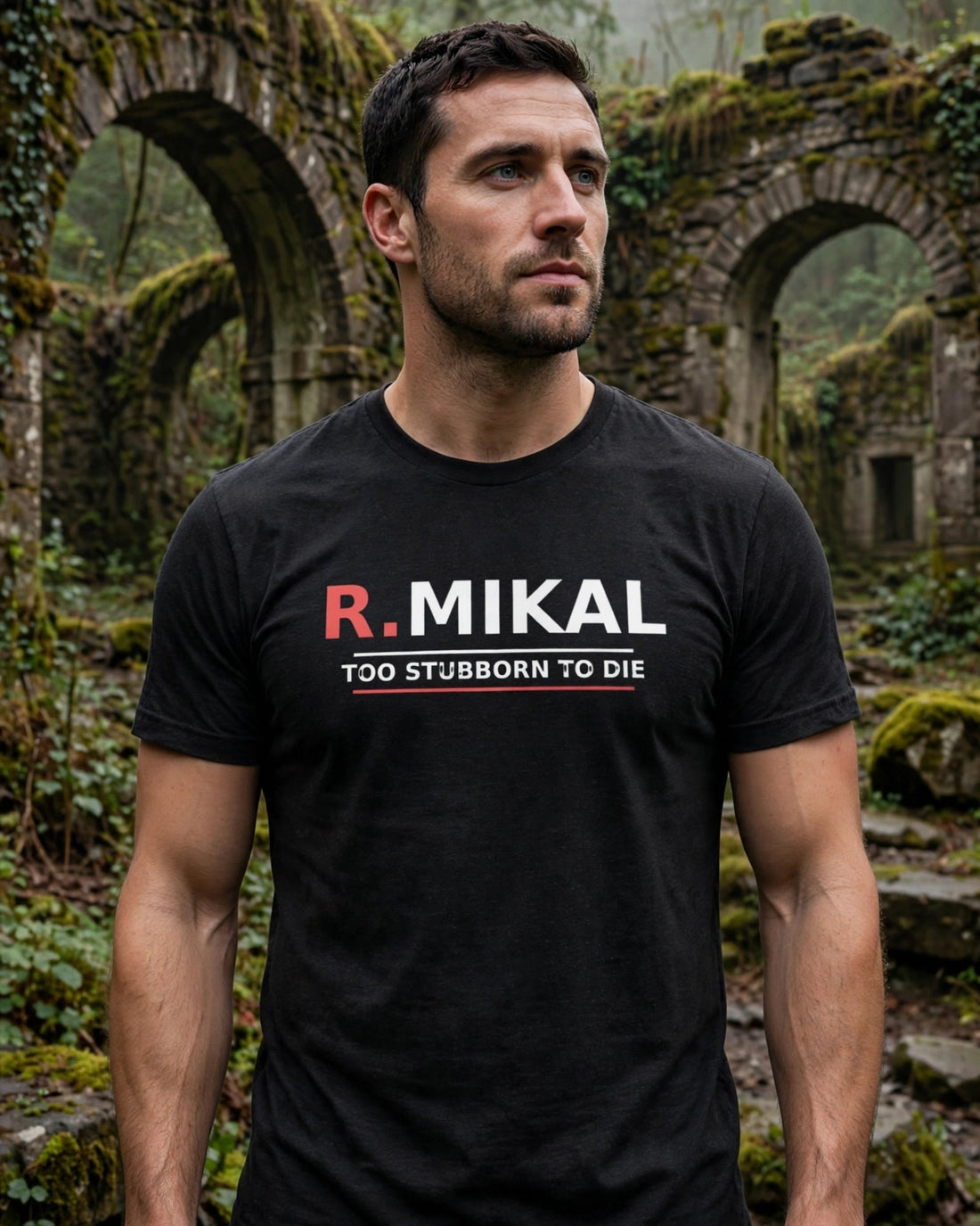 Man wearing the black heather R.Mikal Too Stubborn to Die tee in misty forest ruins, red R. and white MIKAL with TOO STUBBORN TO DIE between white and red lines