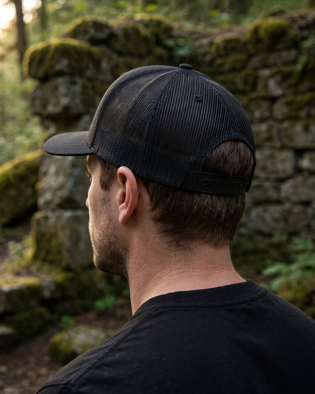 Back of the black R.Mikal trucker hat showing mesh panels and adjustable snapback